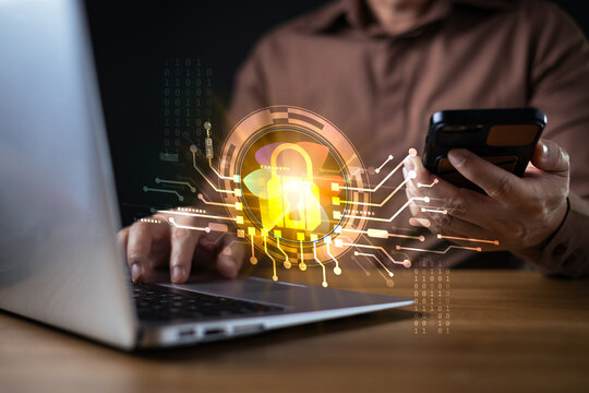 Man using laptop and phone with digital padlock hologram. Concept of cybersecurity, data protection, privacy, network security, and secure internet technology in modern business.