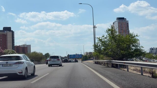 Madrid, Spain, June 30, 2026: Traffic travels along the M-11 beneath motorway signs directing vehicles toward Castellana, Chamartin, Burgos and connecting routes on a summer day. Editorial use only.