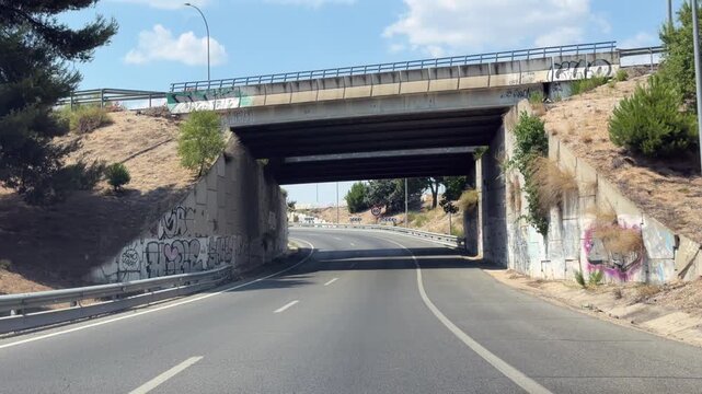 Madrid, Spain, June 30, 2026: Traffic follows a curved M-40 motorway interchange, passing beneath an overpass before continuing along the connecting roadway on a summer day. Editorial use only.