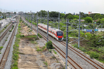Obraz premium Red Commuter Train on the railroad tracks heading towards the City, outdoor landscape.
