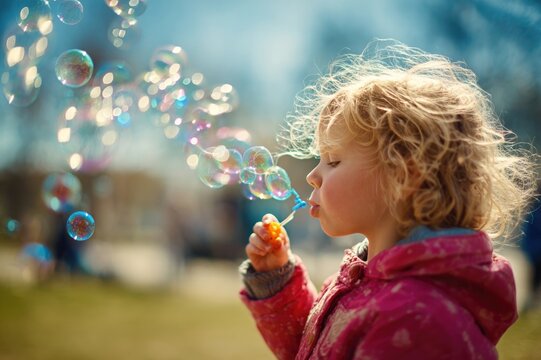 Child blowing soap bubbles instead of smoke, bright outdoor park scene