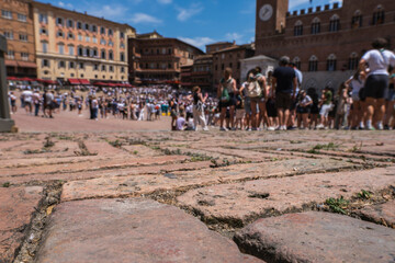 Obraz premium Low angle view of the red brick pavement of Piazza del Campo in Siena, Italy, with a crowd gathering before the historic Palio horse race