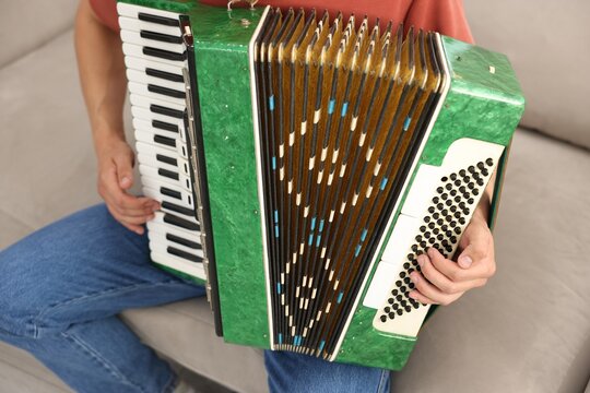 Man playing piano accordion at home, closeup