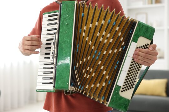 Man playing piano accordion at home, closeup
