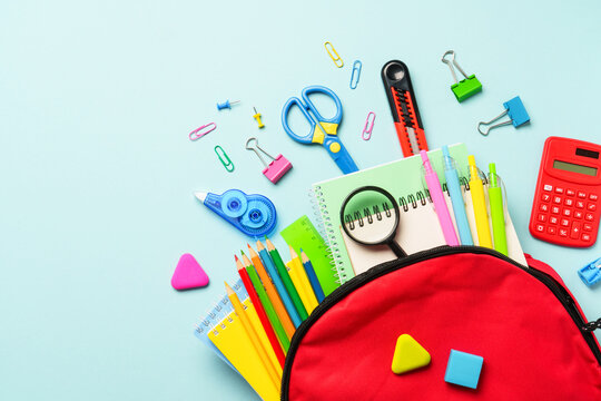 School backpack with stationery on colored background.