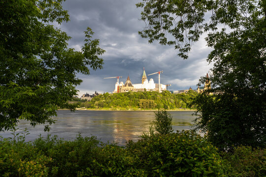 Ottawa River and Parliament Hill framed by green trees in Canada
