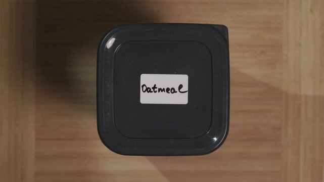 Hands pressing a lid on a container with Oatmeal identification tag