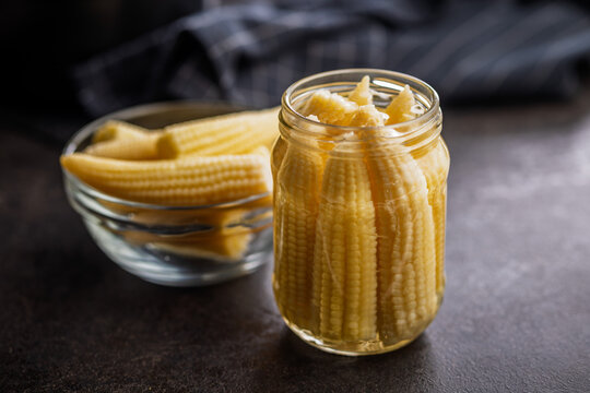 Jar Of Baby Corn Preserved In Glass Jar With Bowl On Dark Kitchen Surface