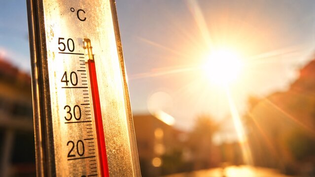 Close-up of a thermometer showing high temperatures under a blazing summer sun