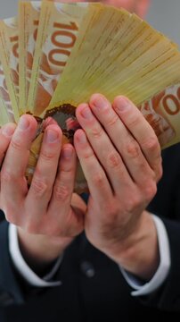 Formally dressed man is counting Canadian Dollar bills, close-up.