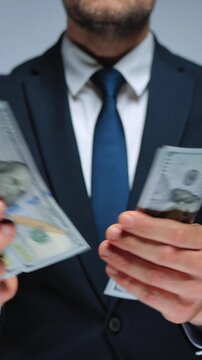 Formally dressed man is counting US Dollar bills, close-up.