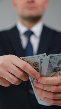 Formally dressed man carelessly throws US Dollar bills towards the camera