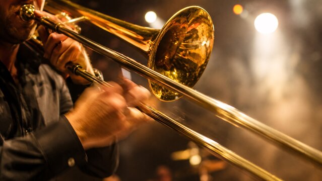 Close-up of a musician's hands playing a golden brass trombone