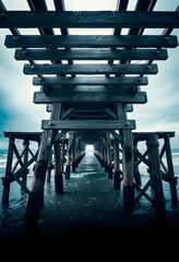 Fototapeta premium underneath wooden pier structure over ocean water