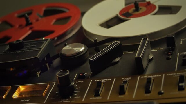 Reel-to-reel tape recorder playing magnetic tape, capturing vintage analog sound. Music production and entertainment, perspective close up shot, background video loop