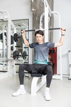 Young man training on lat pulldown machine in modern gym