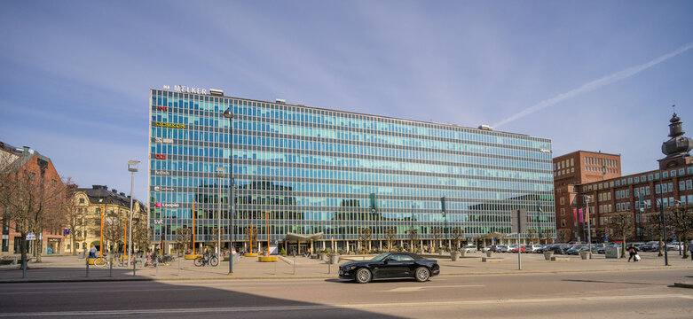 V?ster?s, Sweden - April 18 2026: Large office building complex with glass facade and cars passing on wide urban avenue.