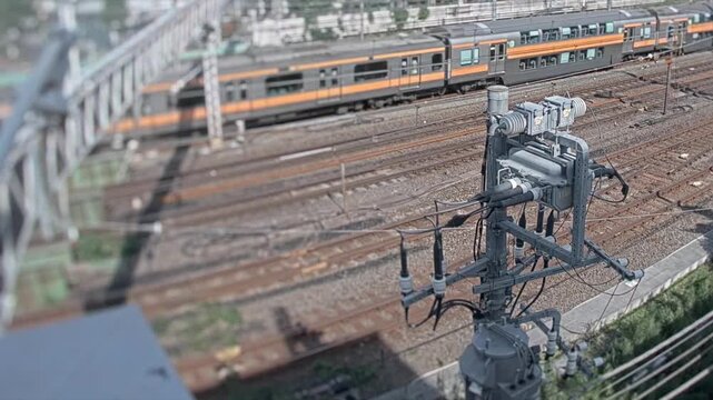 Timelapse view of multiple railway tracks with a commuter train passing by in Tokyo, Japan. Urban transportation and rail infrastructure scene from an elevated angle.