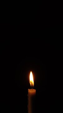 Single Burning Candle Flame in Against Black Dark Vertical Background  