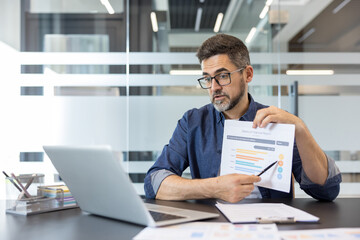 Obraz premium Businessman analyzing and discussing a financial report with charts and data during a virtual meeting, communicating business strategies and market trends while working remotely from an office