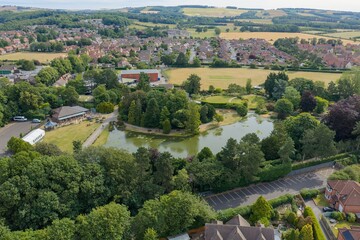 Aerial drone photograph of Burnby Hall Gardens in the market town of Pocklington near York in the East Riding of Yorkshire showing the ornamental lake landscaped gardens surrounding woodland © Duncan