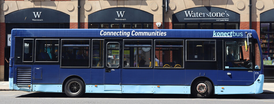 Norwich, United Kingdom - July 5, 2026: General street view in Norwich city centre Blue public bus with yellow handrails parked front of retail stores an urban setting