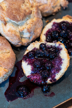 Homemade biscuits on a square platter, split open and topped with hand crafted blueberry sauce, delicious summer food treat
