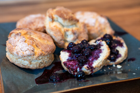 Homemade biscuits on a square platter, split open and topped with hand crafted blueberry sauce, delicious summer food treat
