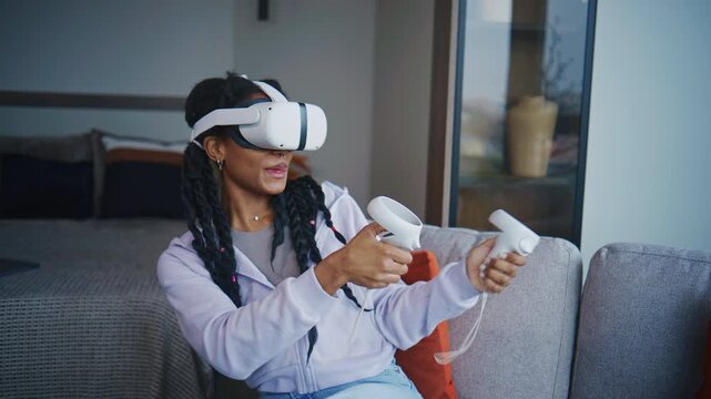 Girl plays virtual reality game at home in the living room with VR headset and controllers