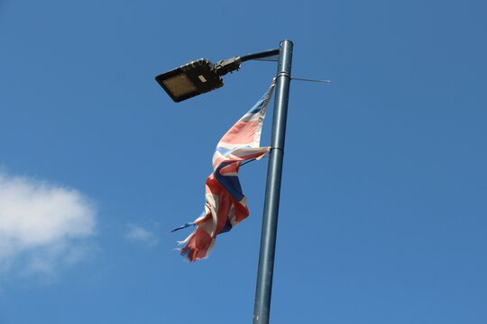 A ripped Great Britain flag blows in the wind on a sunny day