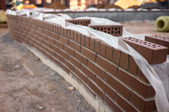 construction worker carefully applying mortar to bricks on a building site, focused and industrious mood, close-up of the bricklaying process, brown and gray bricks, concrete bricks, masoni.