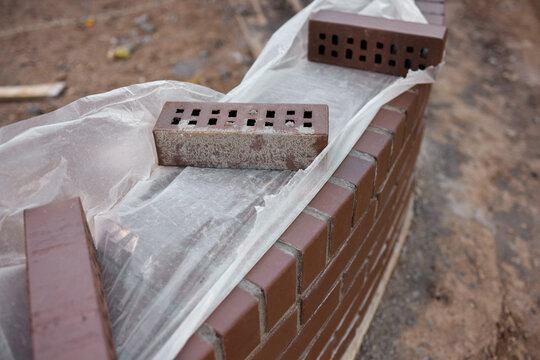 construction worker carefully applying mortar to bricks on a building site, focused and industrious mood, close-up of the bricklaying process, brown and gray bricks, concrete bricks, masoni.