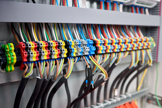 connected and organized electrical wiring in an indoor panel with a close-up perspective showing terminal blocks and cable ties against a clean background with black and red wires.