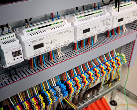 connected and organized electrical wiring in an indoor panel with a close-up perspective showing terminal blocks and cable ties against a clean background with black and red wires.