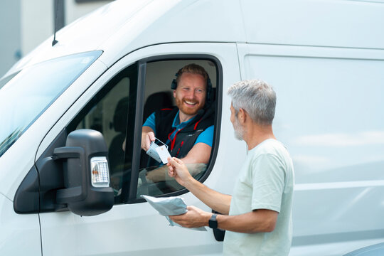 Customer makes a contactless payment using a handheld payment terminal while receiving a parcel from a courier.