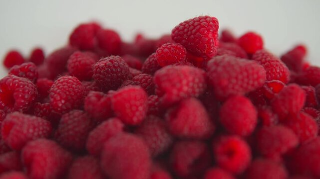Fresh raspberries piling up in a macro view on a white background showing healthy organic food and vitamins