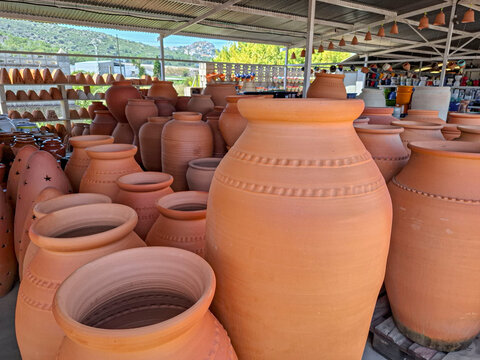 Rows of large traditional Mediterranean clay amphoras and rustic terracotta pots in an outdoor pottery market during the day