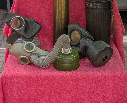 Vintage military gas masks and filter canisters from World War II displayed on a red background as collectibles