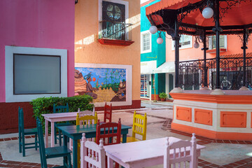 Colorful mexican plaza with traditional mural and outdoor seating © Kai Grim
