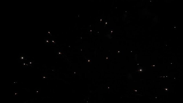 Firework explosions with glowing traces and stars in sky at nighttime holiday. Brilliant display of firework flashes illuminate black sky. Firework performance for spectators at evening party