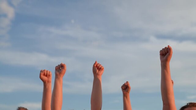 People raise their hands together, voting with their fists. Business team unity partners. Teamwork. Group people against sky raise their fists. Voluntary voting, expressing consent, supporting freedom