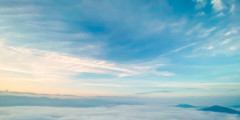 Fototapeta premium Beautiful sunrise landscape background with soft sea of fog over mountains and clear pastel turquoise blue sky for panoramic travel design