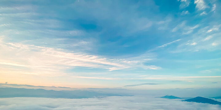 Beautiful sunrise landscape background with soft sea of fog over mountains and clear pastel turquoise blue sky for panoramic travel design