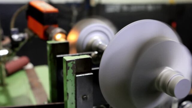 Close-up of a large metallic turbocharger turbine wheel rotor set up on a dynamic balancing rig with adjustment scales in a precise engineering workshop.