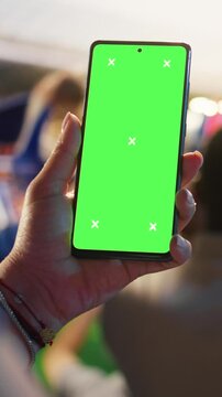 Portrait video: Close-up of isolated screen mobile phone used by soccer fan to compare match odds, cheering in stadium.