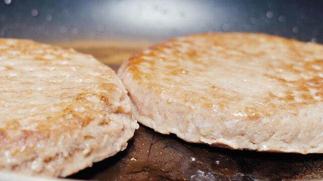 Glistening hamburger patties frying and searing in hot skillet pan