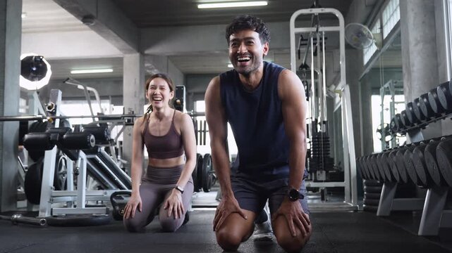 Happy man and woman laughing after a gym workout, promoting fitness, teamwork, motivation, healthy lifestyle and shared exercise.