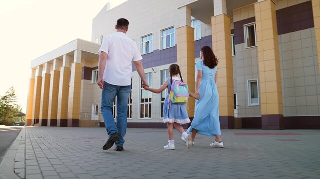 mother father leading child school holding hands, happy family, father mother holding child hands, family holding hand against backdrop school building, father mother escorting child school backpack