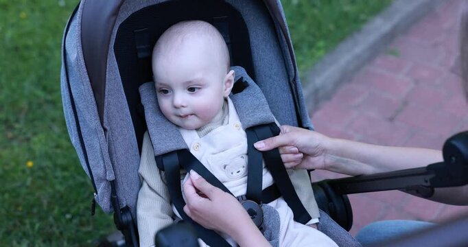 Mother with her cute baby in stroller at park. Camera moving forward