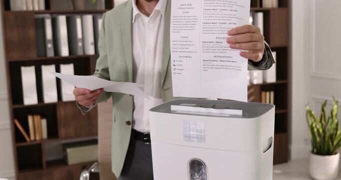 Man destroying documents with shredder in office, closeup